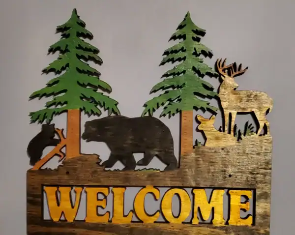 Wooden wildlife welcome sign featuring bears, deer, and pine trees for rustic home decor.