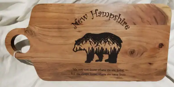 Custom engraved New Hampshire bear-shaped wooden charcuterie board with home quote.