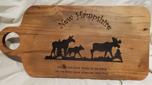 Moose family engraved on wooden charcuterie board, perfect for New Hampshire decor.