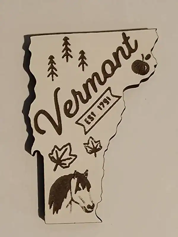 Vermont state magnet with engraved trees, horse, and bear design.