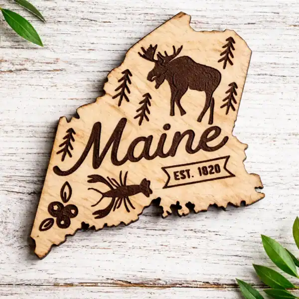 Maine state laser engraved magnet with moose, pine trees, and berries, perfect for souvenirs or home.
