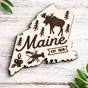 Maine state laser engraved magnet featuring a moose, pine trees, and "Maine" text, perfect for souve.