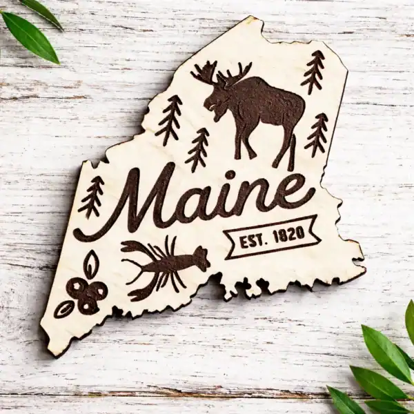 Maine state laser engraved magnet featuring a moose, pine trees, and "Maine" text, perfect for souve.