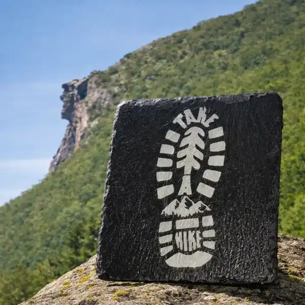 Engraved boot print design on black slate coaster for outdoor enthusiasts.