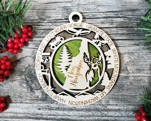 Laser engraved New Hampshire state ornament with nature and mountain design.